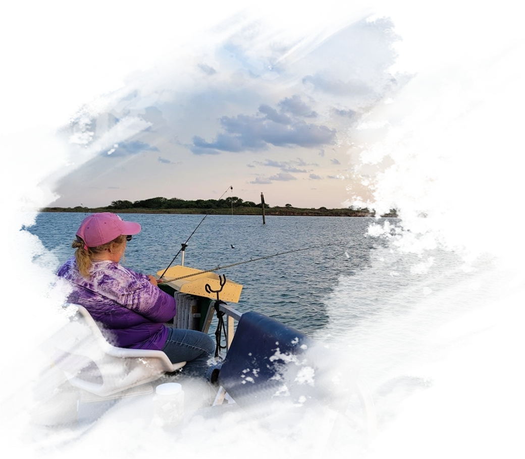 A woman fishing on the water with a pink hat.